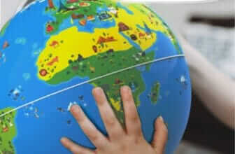 "Child's hand on the Orboot Earth interactive globe without borders or names, suggesting exploration and learning."