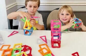 "Two children engaging with colorful Coodoo magnetic blocks, constructing imaginative shapes on a white table." "Two children engaging with colorful Coodoo magnetic blocks, constructing imaginative shapes on a white table."